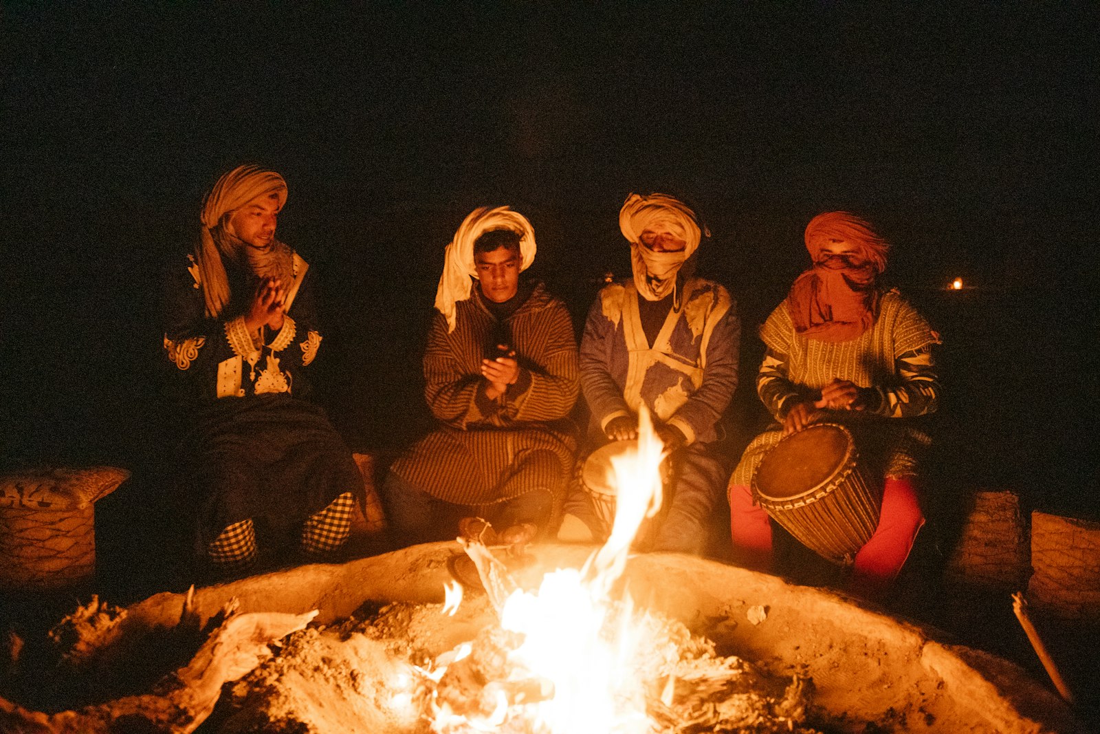 Travellers and Berber musicians around a campfire in the desert